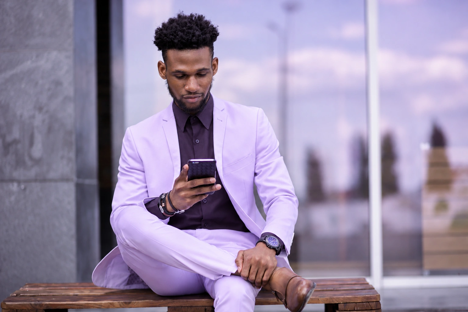 Man in a lavender suit checking his phone outdoors